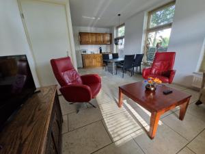 sala de estar con sillas rojas y mesa en Borger appartement in centrum dorp., en Borger