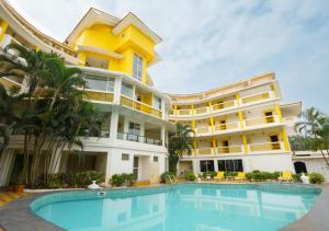 a large building with a swimming pool in front of it at Bloom Boutique Baga in Baga