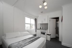 a white bedroom with a bed and a kitchen at Flexistay Tulsi Aparthotel in Croydon