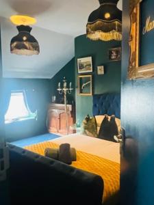 a bedroom with a bed with yellow sheets and blue walls at The Gin Lounge Rooms in Ilkley