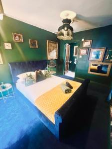 a bedroom with a large bed with green walls at The Gin Lounge Rooms in Ilkley