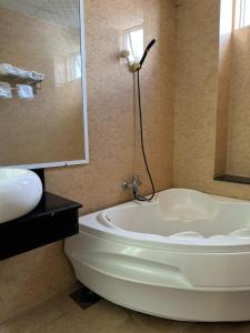 ein Badezimmer mit einer weißen Badewanne und einem Waschbecken in der Unterkunft Bình Minh Motel in Pleiku