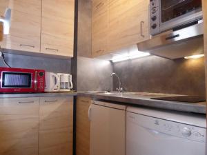 a kitchen with a red microwave and a sink at Charmant appartement rénové 2/3 pièces pour 5 pers, proche pistes et commerces, parking gratuit - FR-1-329-29 in Bellentre +4 photos