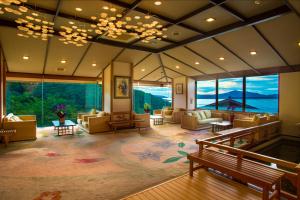 a large room with couches and tables and windows at Hanashinsui in Toba