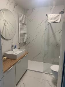 a white bathroom with a sink and a mirror at Apartament Hebanowa in Swarzędz