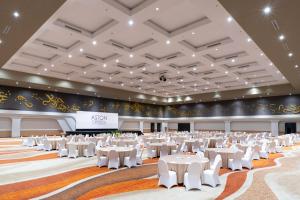 une grande salle de banquet avec des tables et des chaises blanches dans l'établissement ASTON Cirebon Hotel and Convention Center, à Cirebon