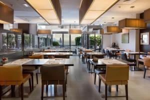 a restaurant with tables and chairs and large windows at Hotel & Spa Villa Olimpica Suites in Barcelona +13 photos