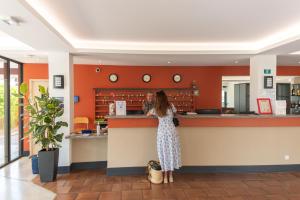 a woman standing at a counter in a restaurant at Residence Agathea in Cap d'Agde