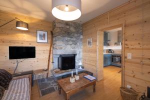 a living room with a stone fireplace and a television at St Gervais Les Bains - Mont Blanc in Saint-Gervais-les-Bains