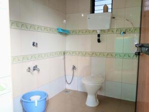 a bathroom with a toilet and a bucket in it at The Grace Guest House in Salcete