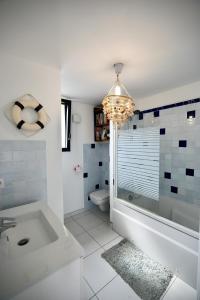 a bathroom with a tub and a toilet and a chandelier at Duplex vue mer plage de Saint-Clair in Le Lavandou