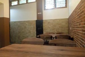 a room with chairs and a table and a brick wall at Pondok Backpacker City Square Malang in Bunul