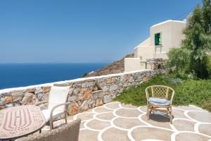 a patio with two chairs and a stone wall at Antiparos in Sikinos