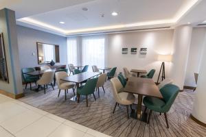 a waiting room with tables and green chairs at Hampton by Hilton Bournemouth in Bournemouth