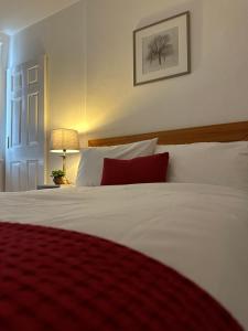 a bedroom with a white bed with a red pillow at Cosy Cambridge Centre Flat in Chesterton