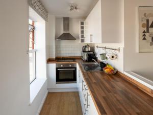cocina con armarios blancos y suelo de madera en Pass the Keys Modern Stylish apartment with parking, en Bournemouth