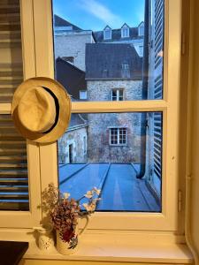 a window with a hat and a view of a tennis court at Studio dans une grande maison médiévale au centre historique de Laval in Laval