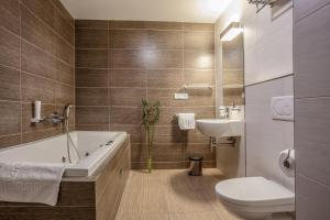 a bathroom with a tub and a toilet and a sink at Hotel Lidový dům in Bzenec