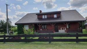a red house with a fence in front of it at Agro Karasiewo in Karasiewo