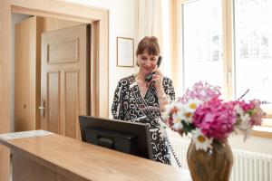 a woman talking on a phone in front of a desk with a computer at Gästehaus Salvatorianerinnen in Merano