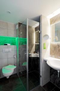 a bathroom with a shower and two sinks and a toilet at Bio-Seehotel Zeulenroda in Zeulenroda