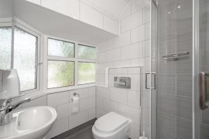 a white bathroom with a toilet and a sink at Flexistay Aparthotel Sutton in Sutton