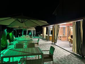 a patio with tables and chairs and umbrellas at night at Pesvebi Design Hotel and Cellar in Borjomi