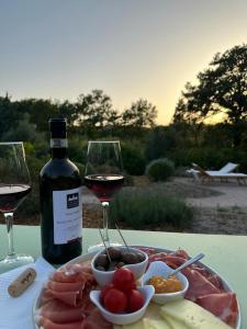 a plate of meat and a bottle of wine and wine glasses at Casale Terre Rosse Garden in Saturnia