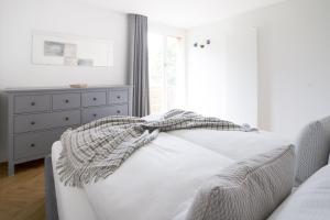 a white bedroom with a bed and a dresser at Central Serviced Apartments in Engelberg