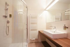 a white bathroom with a sink and a shower at Gästehaus Salvatorianerinnen in Merano