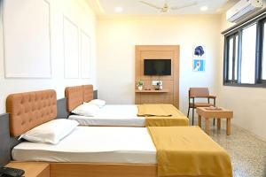 a bedroom with two beds and a television in it at PRINCE RESIDENCY CLUB HOUSE in Jamnagar