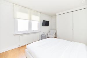 a white bedroom with a white bed and a window at The Hampstead Heath Escape - Trendy 1BDR Flat with Balcony in London