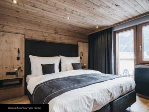 1 dormitorio con 1 cama grande y techo de madera en Chalet Pfunds, en Pfunds