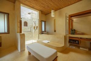 a bathroom with a tub and a shower and a bench at High Season Pool Villa & Spa in Ko Kood