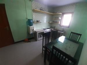 cocina con mesa, fogones, mesa y sillas en Widodaren Homestay en Probolinggo