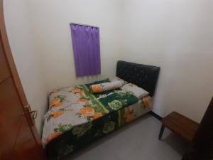 Dormitorio pequeño con cama con edredón y almohadas en Widodaren Homestay en Probolinggo