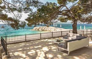 a bench sitting under a tree next to the ocean at Villa Berulia in Brela