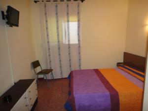 - une chambre avec un lit, une chaise et une télévision dans l'établissement Pensió Restaurant Llança, à Llançà