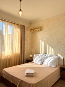 um quarto com uma cama com lençóis brancos e uma janela em BATUMI KEY 8 em Batumi