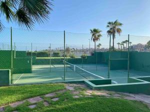 zwei Tennisplätze mit Palmen und einem Zaun in der Unterkunft Piso en primera línea de playa, Vera Playa in Playas de Vera