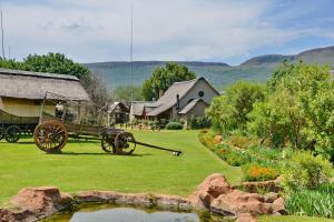a garden with a horse drawn carriage and a pond at African Hills Safari Lodge & Spa in Magaliesburg