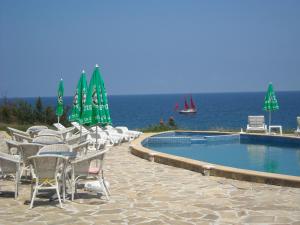 a pool with chairs and umbrellas next to the ocean at Aparthotel Romance in Kiten