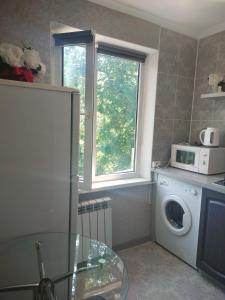uma cozinha com uma máquina de lavar roupa e uma janela em Квартира на Панфилова "Арбат" 1 комн em Almaty