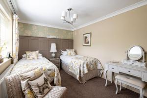 1 dormitorio con 2 camas, escritorio y espejo en Primrose Cottage en Whitby