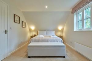 a white bedroom with a bed and a window at Butler's Barn in Newmarket