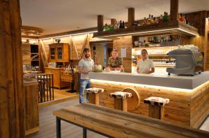 un gruppo di tre persone in piedi in un bar di Hotel Cime D'Oro a Madonna di Campiglio