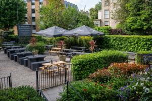 een patio met tafels en parasols in een tuin bij Channings Hotel by Greene King Inns in Bristol