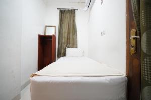 Cama pequeña en habitación con ventana en Griya Sawamah Syariah Mitra RedDoorz, en Yakarta