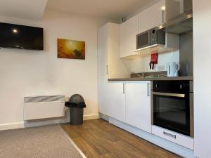 a kitchen with white cabinets and a black oven at Pass the Keys Centrally located Studio Apartment in Lincoln