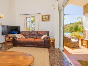 a living room with a leather couch and a television at Cubo's Casa Rural Las Brisas in Alhaurín el Grande